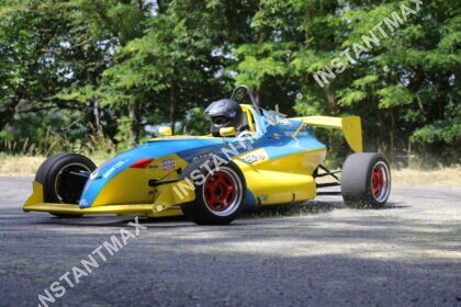 Monoplace de compétition bleu et jaune en pleine attaque dans un virage