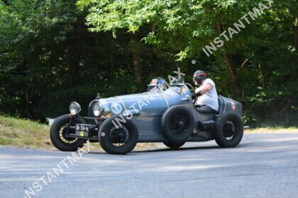 Voiture de course historique vintage en action sur route lors d’une compétition automobile
